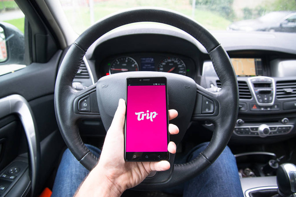 Driver holding smartphone with Trip.com application - Foto, afbeelding