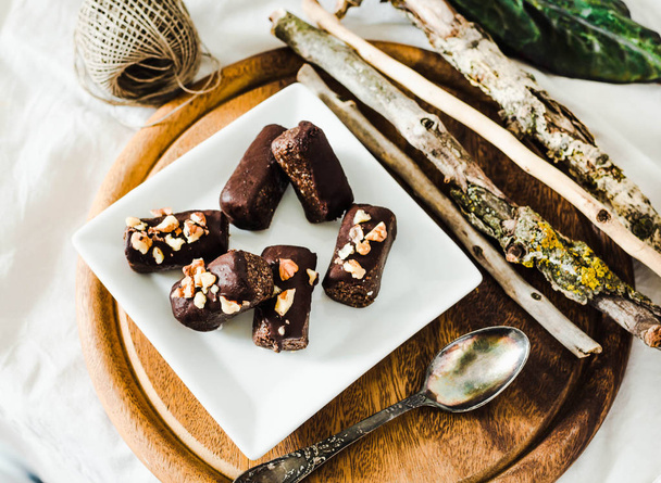 healthy raw chocolate candies with walnuts on a white square pla - Foto, Bild