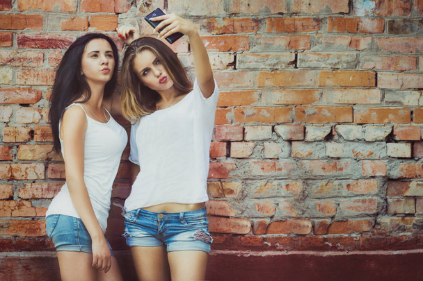 girlfriends taking a selfie in urban city context. Concept of friendship and fun with new trends and technology - Photo, Image