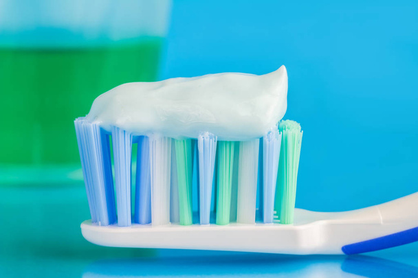 歯ブラシの上の歯磨き粉、青の背景に緑の歯ブラシ、前景に焦点を当て、マクロ画像 - 写真・画像
