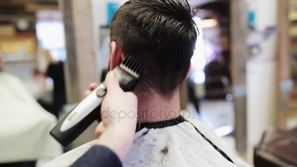 man and stylist doing haircut at barber shop - Filmati, video
