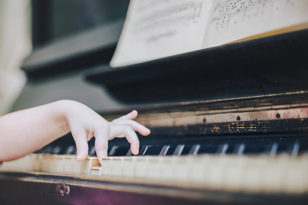 Children's fingers on the keys of a piano playing. - Foto, Imagen