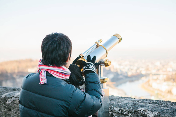 Mladý muž s dítětem vypadá pozorovací dalekohled na ochozu na kopci v rakouské město Salzburg - rodné město Mozarta. - Fotografie, Obrázek
