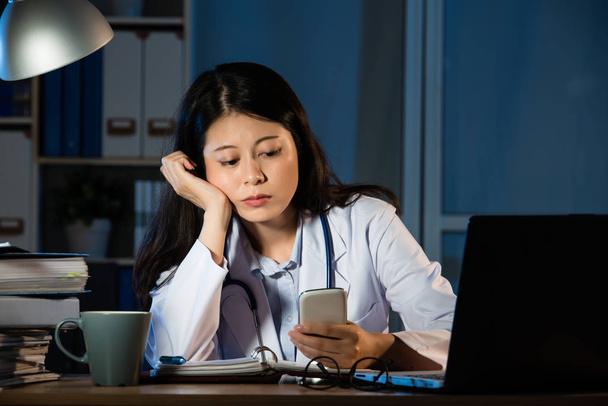 γυναίκα ιατρός εργάζεται σε γραφείο, χρησιμοποιώντας το smartphone - Φωτογραφία, εικόνα