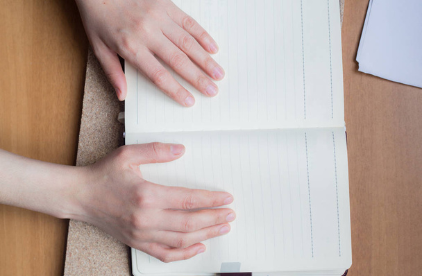 Жіночі руки тримають щоденник на дерев'яному столі. З пробілом для тексту
 - Фото, зображення