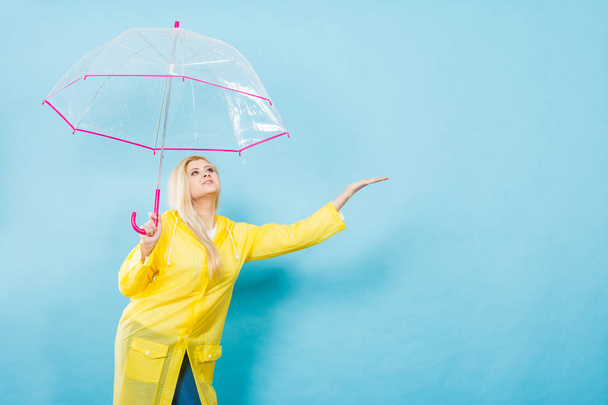 Woman wearing raincoat holding umbrella checking weather - Foto, imagen