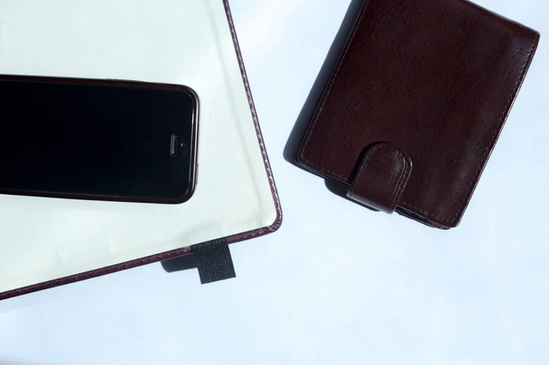 Notebook vazio, telefone celular e uma carteira no fundo branco. .. Com espaço para texto
 - Foto, Imagem