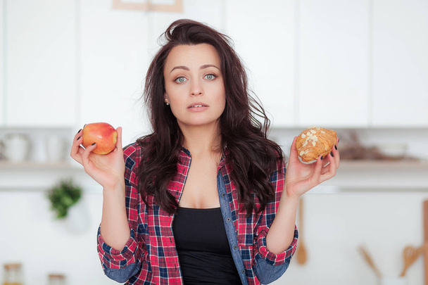 Dieta. Il concetto di dieta. Cibo sano. Bella giovane donna a scelta tra frutta e dolci. Perdita di peso
 - Foto, immagini