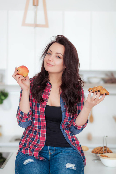 ダイエット。ダイエットの概念。健康食品。美しい若い女性は果物やお菓子の間を選択します。重量の損失 - 写真・画像