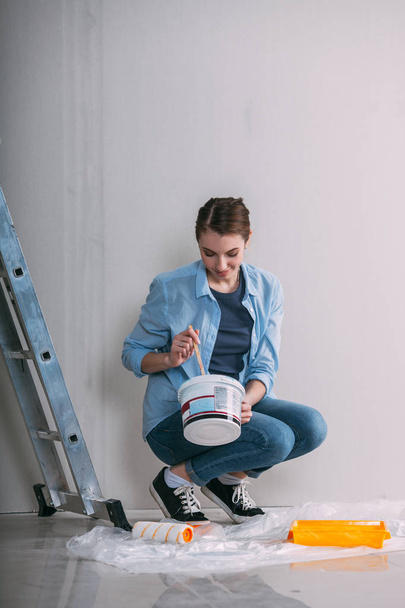 woman sitting on the floor and mixing wall paint - Fotoğraf, Görsel