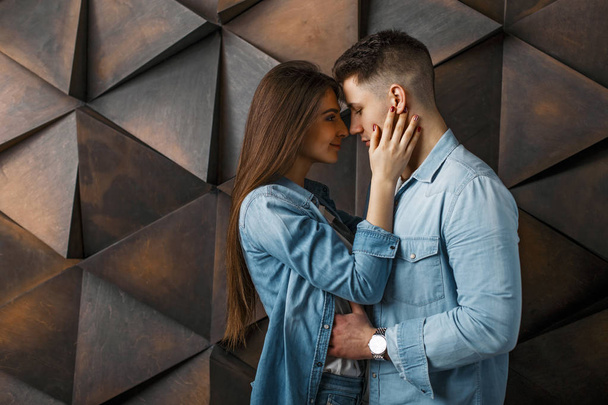 Young stylish couple in jeans clothes near a wooden vintage wall - Photo, Image