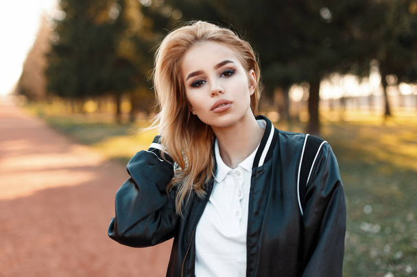 Portrait of a beautiful blond woman in a bomber jacket in white polo on a sunny day - Foto, imagen