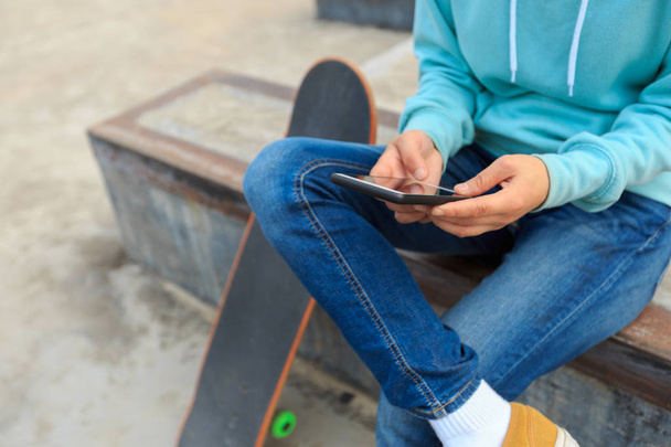 молодий скейтбордист за допомогою смартфона
 - Фото, зображення