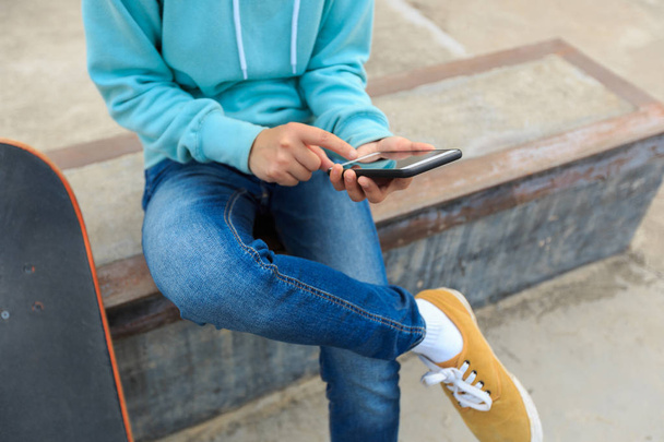 Young skateboarder using smartphone - Zdjęcie, obraz