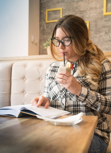 Pretty girl with glasses drinking strawberry bannana smoothie an - Фото, изображение