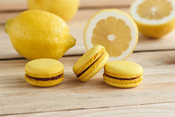 Yellow french macarons with lemons on the wooden boards - Foto, Imagen