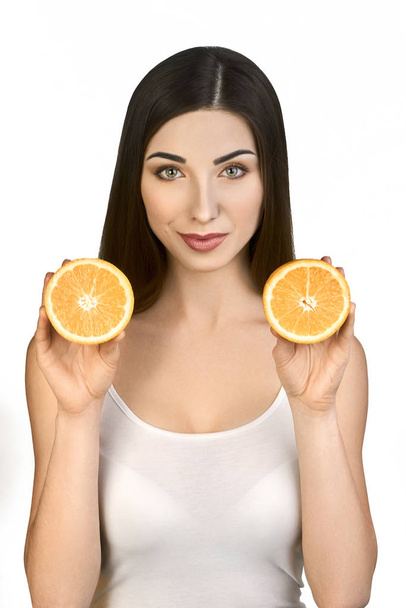 Retrato de morena bonita com duas metades de laranja nas mãos Olhando para a câmera em fundo branco
. - Foto, Imagem