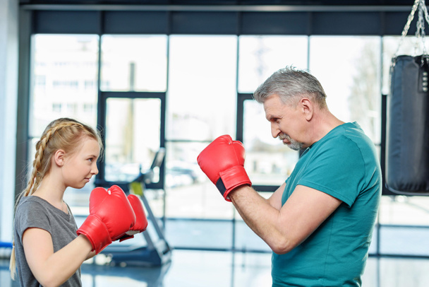 preteen girl boxing with trainer. - Foto, afbeelding