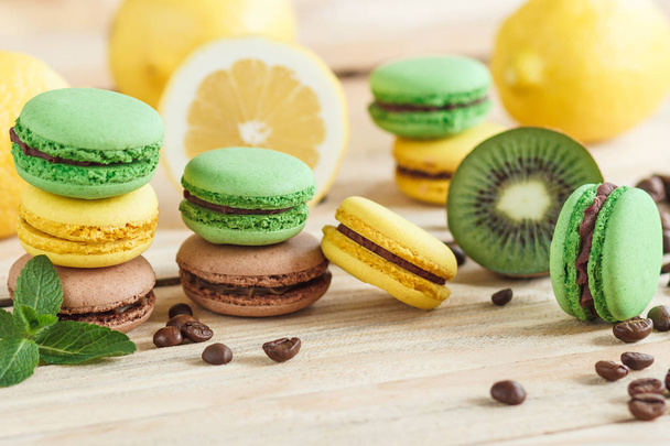 Green, yellow and brown french macarons with kiwi coffee beans and mint decorations - Foto, immagini