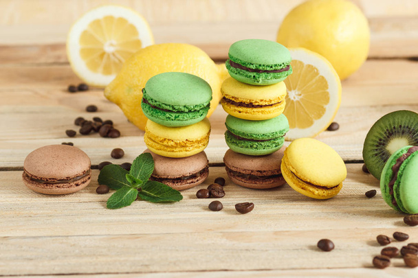 Green, yellow and brown french macarons with kiwi coffee beans and mint decorations - Zdjęcie, obraz