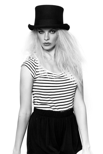 Mooi blond meisje dragen gestreept t-shirt en zwarte hoed zwart-wit - Foto, afbeelding