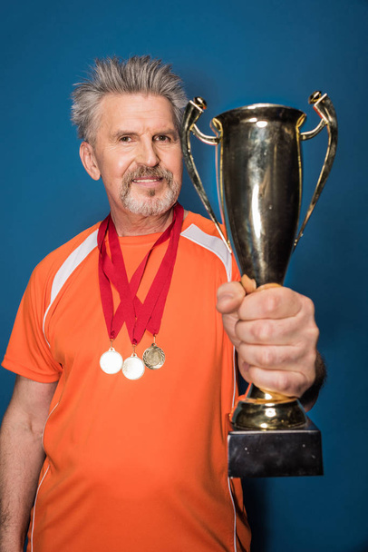 Старший спортсмен с трофеем
   - Фото, изображение