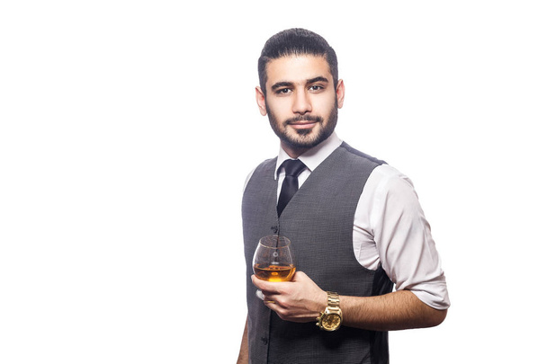 Handsome bearded businessman holding a glass of whiskey.  - Zdjęcie, obraz