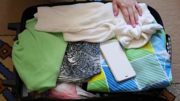 Dziewczyna stawia rzeczy w walizce dla podróży w zbliżenie - Materiał filmowy, wideo