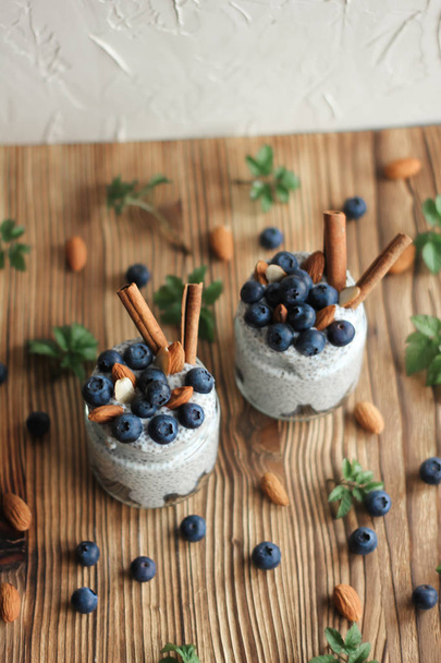 Chia pudding with blueberries and almonds in small bowls on wooden background - Foto, Imagen