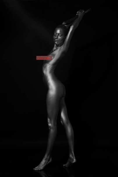 Young slim naked girl on a black background - Photo, Image