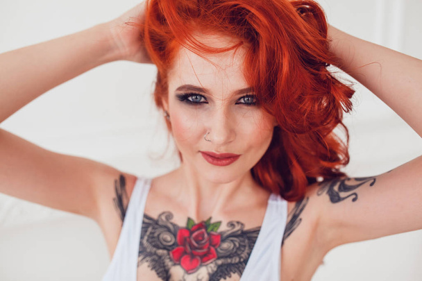 Retrato de uma linda garota sexy com cabelo vermelho e uma tatuagem. Mulher com maquiagem e cachos
. - Foto, Imagem