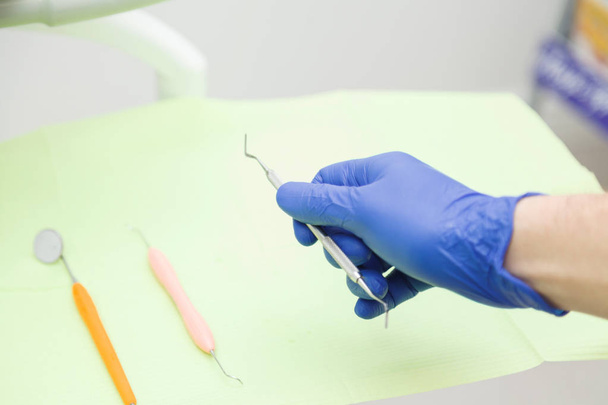 Zahnarzthand in blauem Handschuh nimmt Werkzeug - Foto, Bild