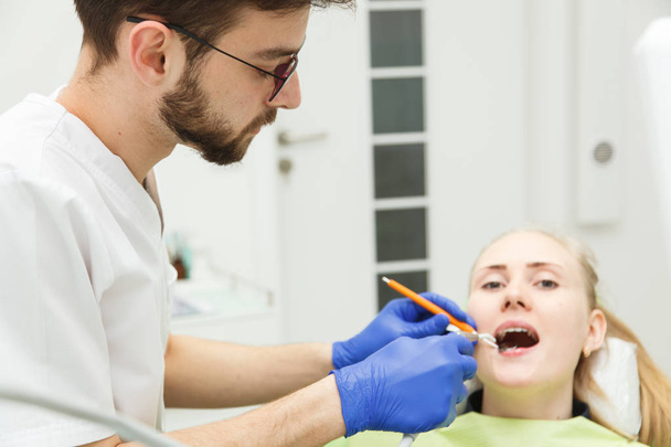 Young male dentist is treating a woman's teeth - Valokuva, kuva