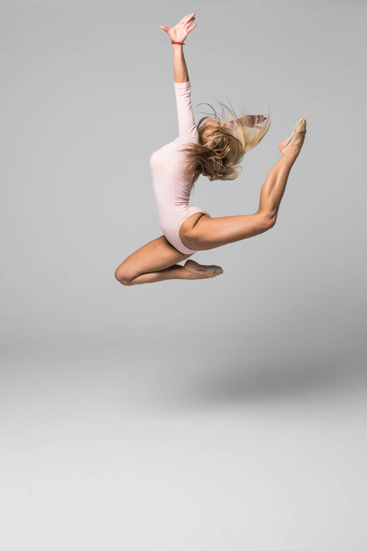 Όμορφη γυναίκα χορεύτρια άλμα με υψηλή πόδι επάνω σε λευκό φόντο - Φωτογραφία, εικόνα