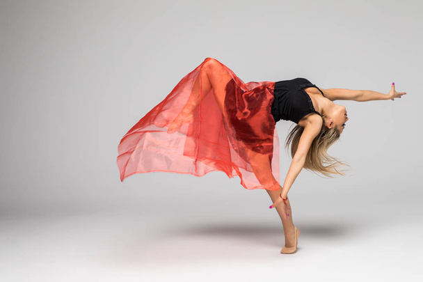 Γυμναστική χορευτής στην εργασία, ο χορευτής με κόκκινο μετάξι στον αέρα σε λευκό φόντο - Φωτογραφία, εικόνα