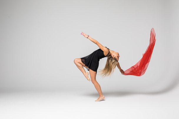 Танцівниця гімнастики в роботі, танцівниця з червоним шовком в повітрі на білому тлі
 - Фото, зображення