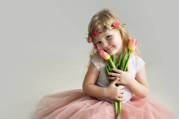 Beautiful girl with tulips on a light background - Photo, image