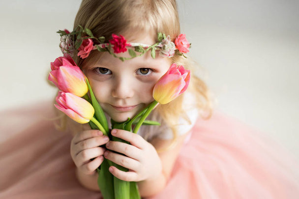 Beautiful girl with tulips on a light background - Fotografie, Obrázek