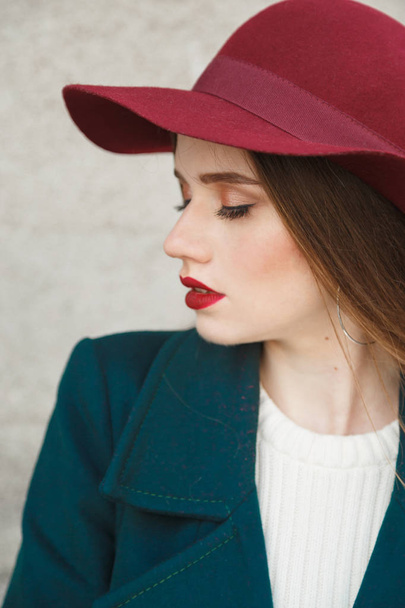 Νεαρή όμορφη γυναίκα προφίλ πορτρέτο. Γυναίκα σε ένα κόκκινο καπέλο στο κεφάλι, όμορφο πρόσωπο και το μαλακό δέρμα. - Φωτογραφία, εικόνα