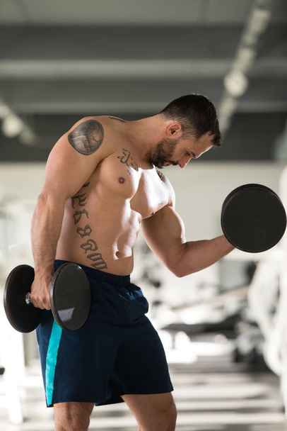 Bodybuilder Exercising Biceps With Dumbbells - Foto, Bild