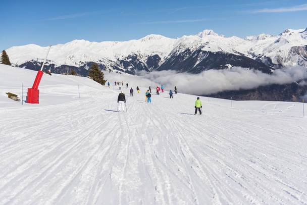 Sciatori su una pista in località sciistica alpina
 - Foto, immagini