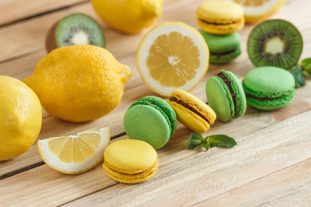Green and yellow french macarons with kiwi, lemon and mint decorations - Foto, immagini