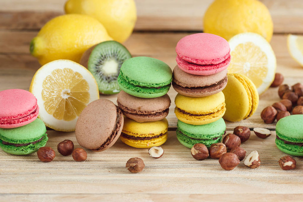 Green, pink, yellow and brown french macarons with lemon, kiwi and hazelnuts - Foto, Bild