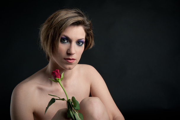Portrait of beautiful girl with rose flower against black background - Photo, Image