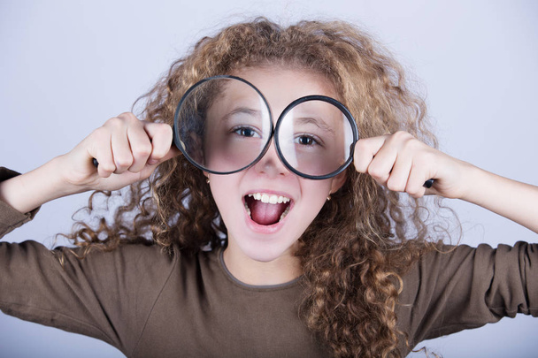Funny portrait of cute little girl looking through  magnifying glass. - Photo, Image