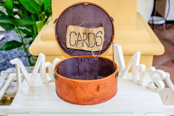 Boîte ronde en cuir marron pour cartes, mots blancs en bois Mr et Mrs sur les côtés. Accessoires de mariage
. - Photo, image