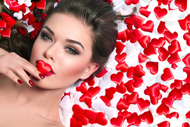 Beautiful young girl with red big lips. Love, Valentine's Day, wedding, romance, tenderness, sensual girl. Tricky glance. Beauty, fashion, cosmetics, makeup.Heart, February 14. - 写真・画像