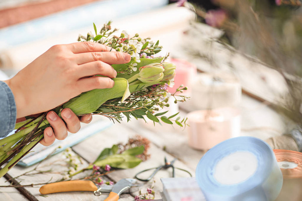 Florist at work: the female hands of woman making fashion modern bouquet of different flowers - 写真・画像