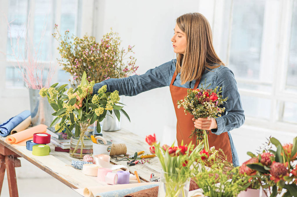 Florist at work: young girl making fashion modern bouquet of different flowers - Foto, Bild