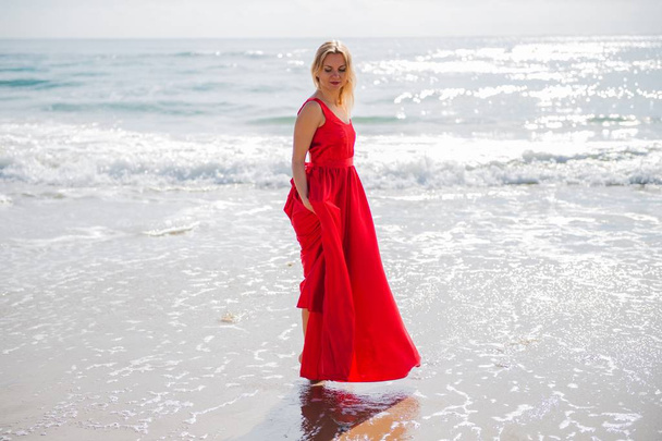 ビーチで赤いドレスの金髪美女 - 写真・画像